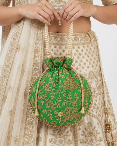 Femme portant un sac potli vert brodé avec anse perlée