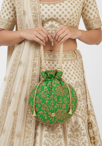 Femme portant un sac potli vert brodé avec anse perlée